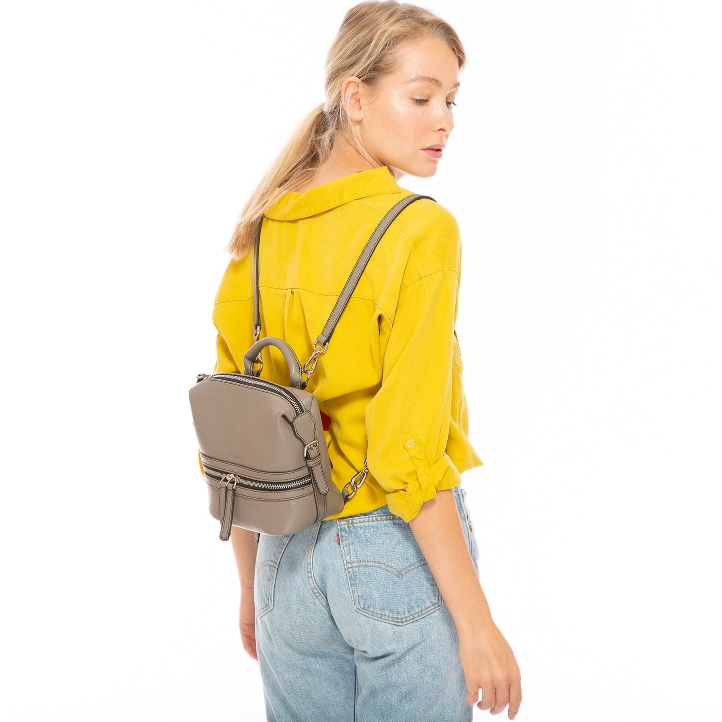 Woman wearing SUSU convertible backpack showing 7.4x7.6x4.6 inch medium size