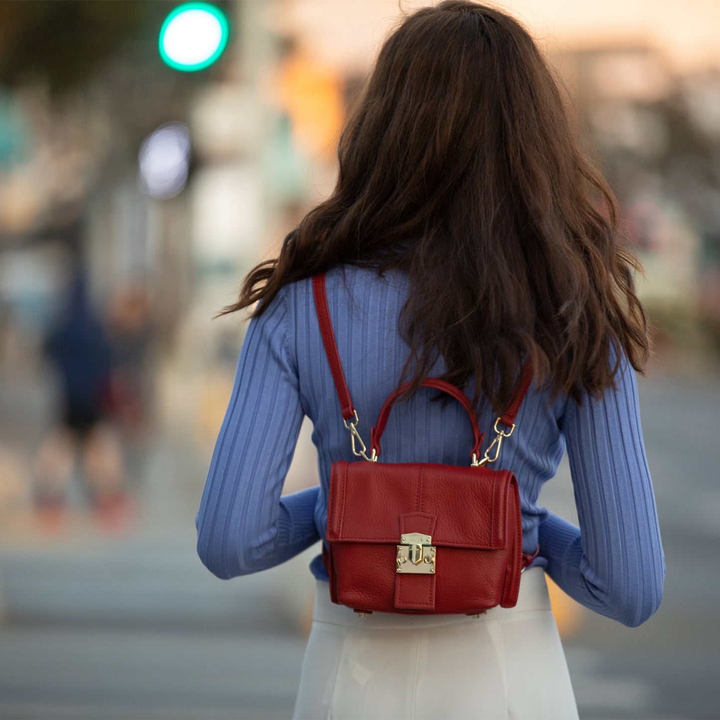 Close-up of SUSU red leather backpack gold magnetic closure and hardware detail