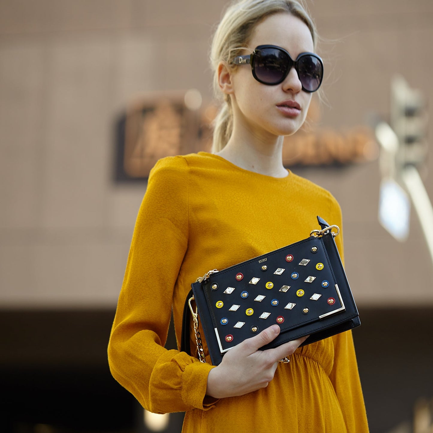 Woman carrying SUSU Austin black studded clutch as evening purse