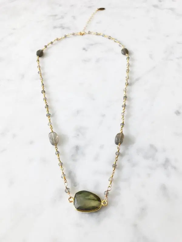 Close-up of Mrs. Parker labradorite stone in 14k gold fill bezel pendant detail on marble background